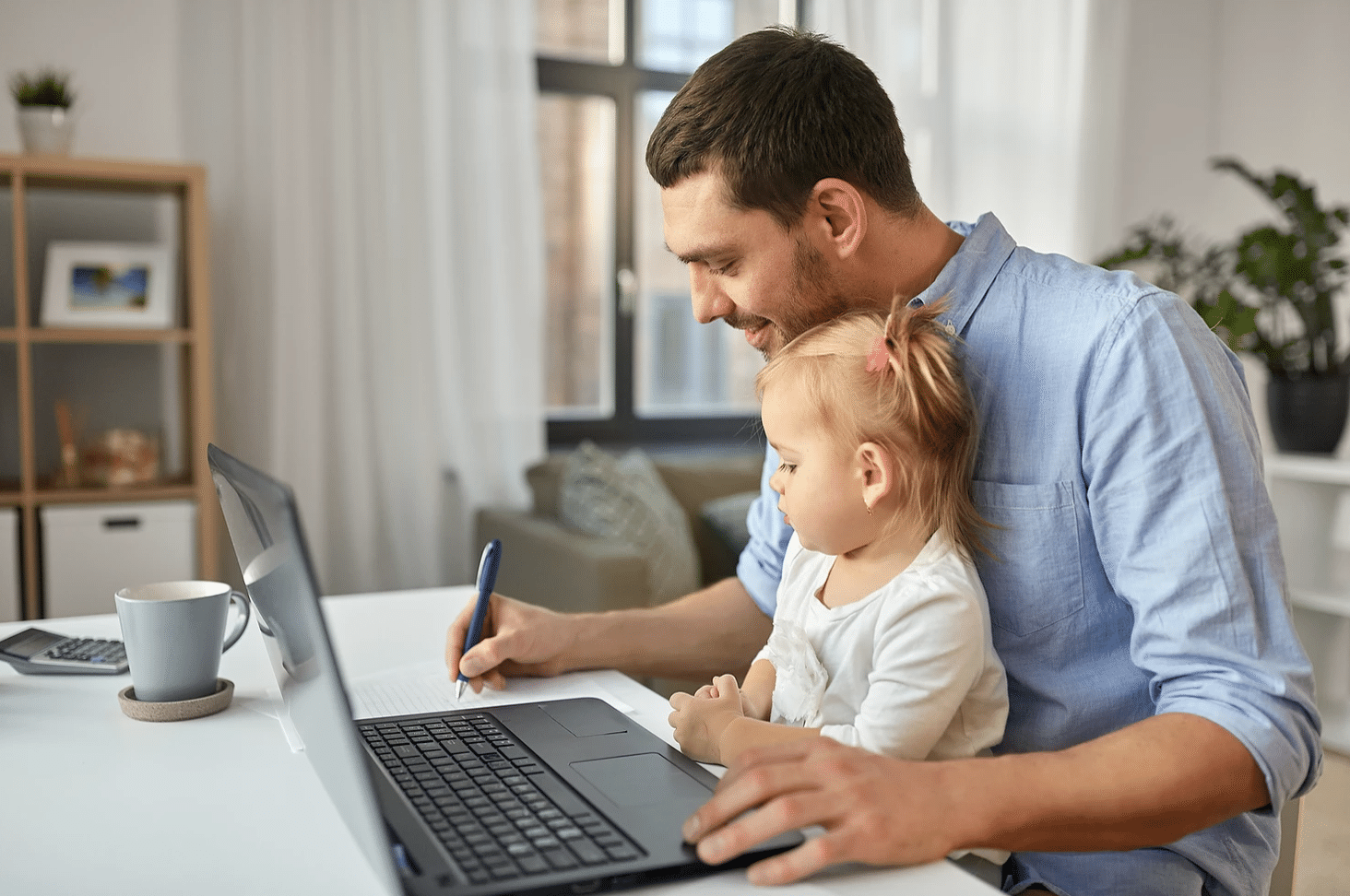 Dad with young daughter on lap will working on laptop
