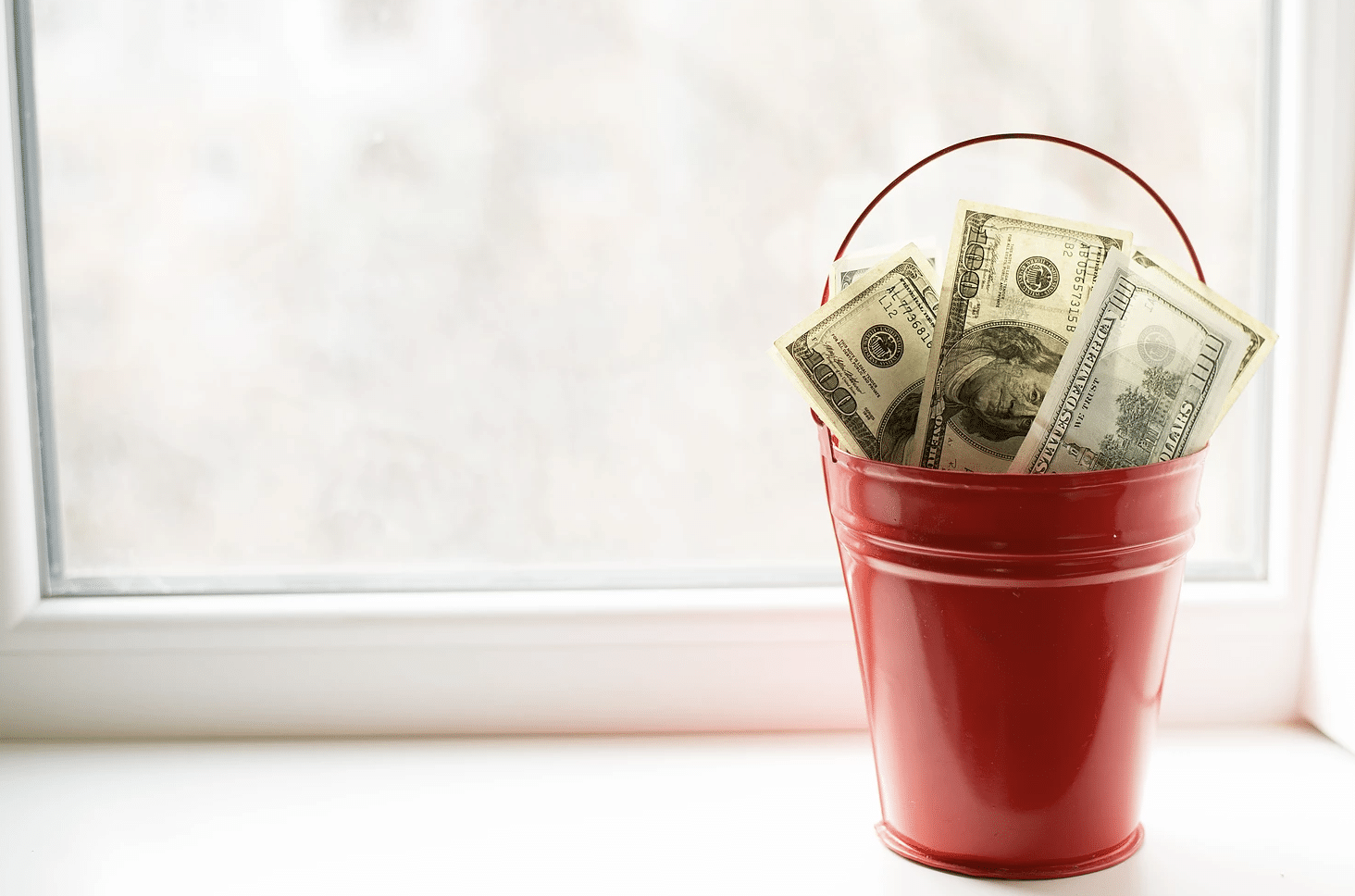 Red bucket filled with $100 bills