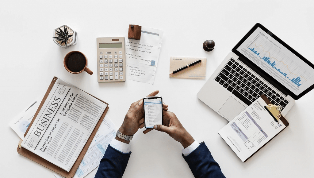 Man looking at mobile phone with financial docs on table