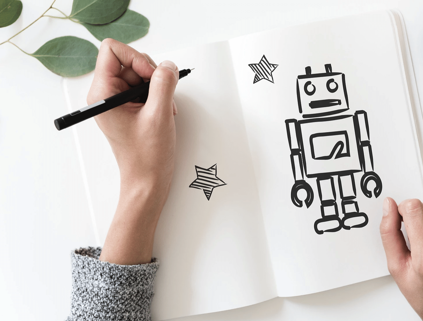 Hand drawing a robot in a notebook