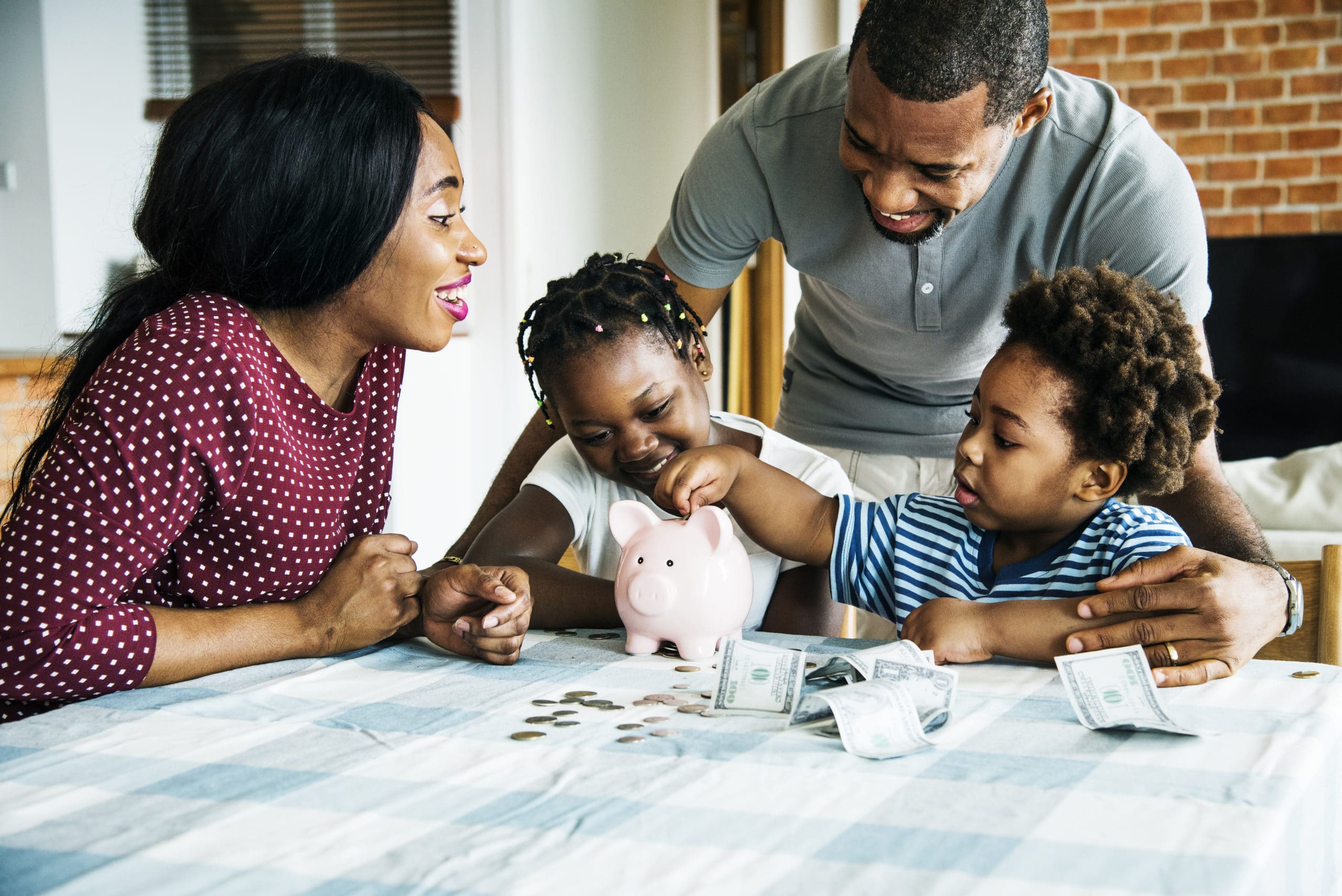 Family of two adults and two children putting money into a piggy bank