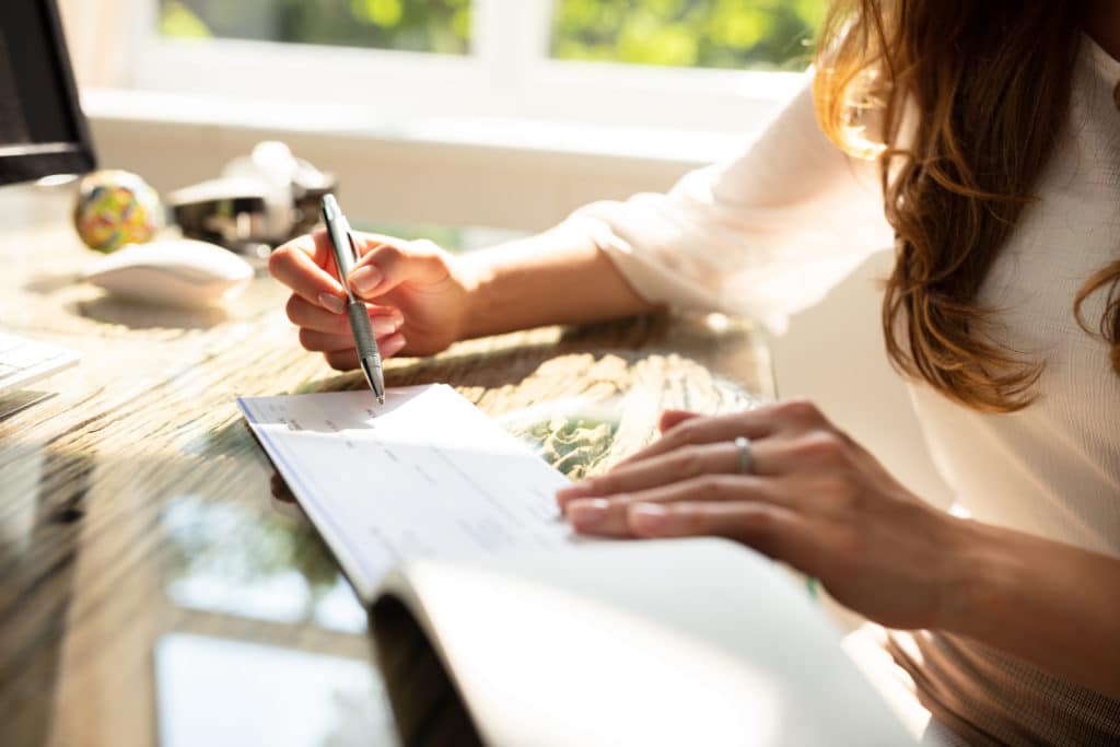 Picture of a woman writing checks on a wooden desk