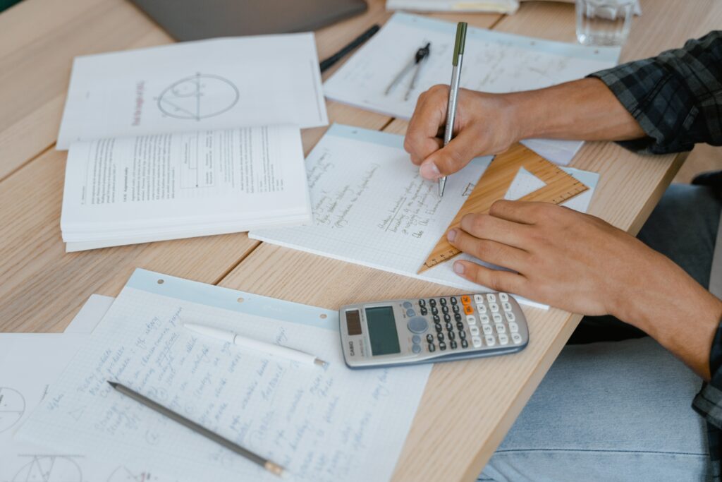 Picture of a person working on a document with many papers and a calculator nearby